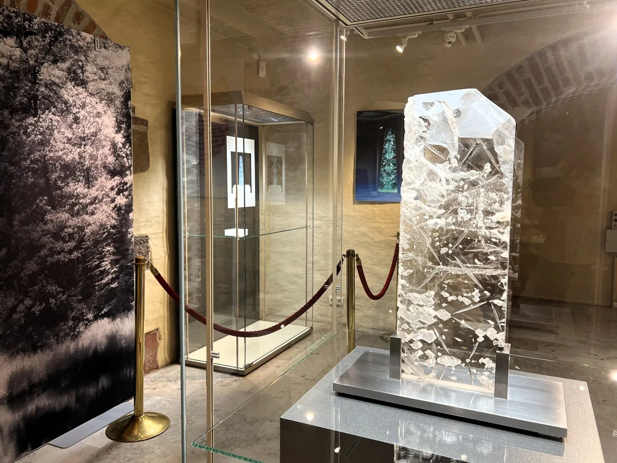 Gro&szlig;er geschliffener Bergkristall auf einem Sockel in der Sonderausstellung &bdquo;Licht, Stein und Vision&ldquo; des Deutschen Edelsteinmuseums, dahinter Vitrinen
